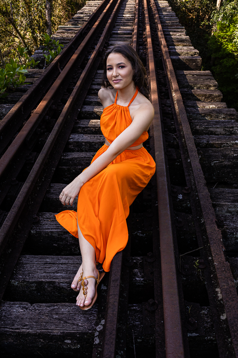 Ensaio de debutante em uma estação de trem com atmosfera vintage. Book de 15 anos que mistura moda e história. Fotografias que destacam a beleza e o estilo da aniversariante.