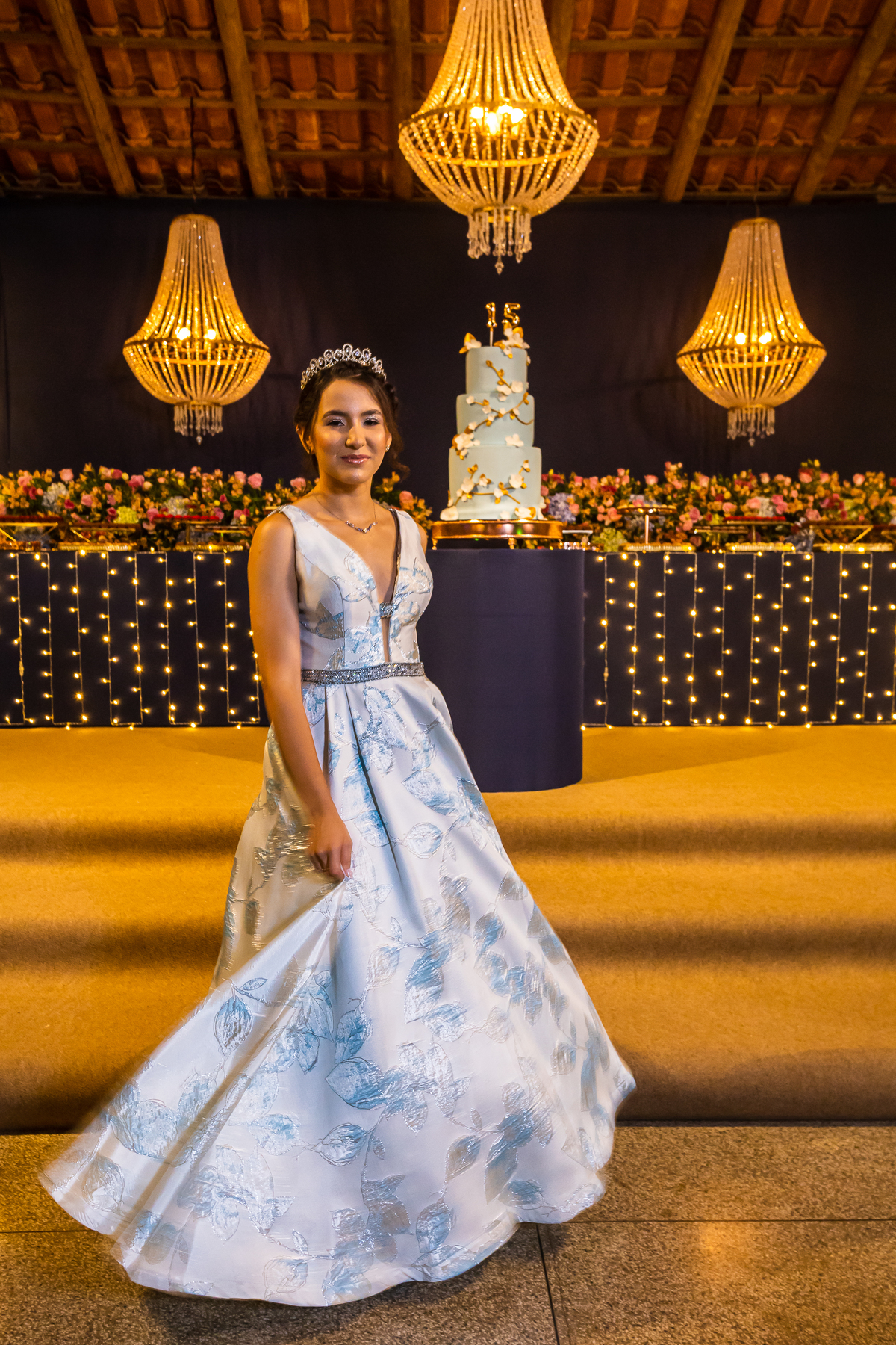 Ensaio de debutante com vestido azul e cenários incríveis em Guarapari. Festa de 15 anos no cerimonial Country Eventos com pista de dança vibrante. Bolo de debutante em destaque na decoração.