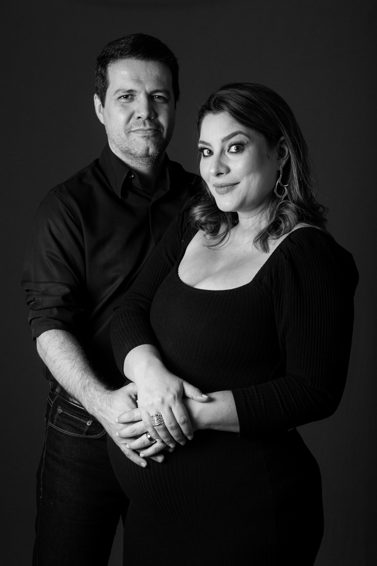 Fotografia de gestante com fundo claro e luz suave. Ensaio de grávida em estúdio com foco no olhar e na barriga.