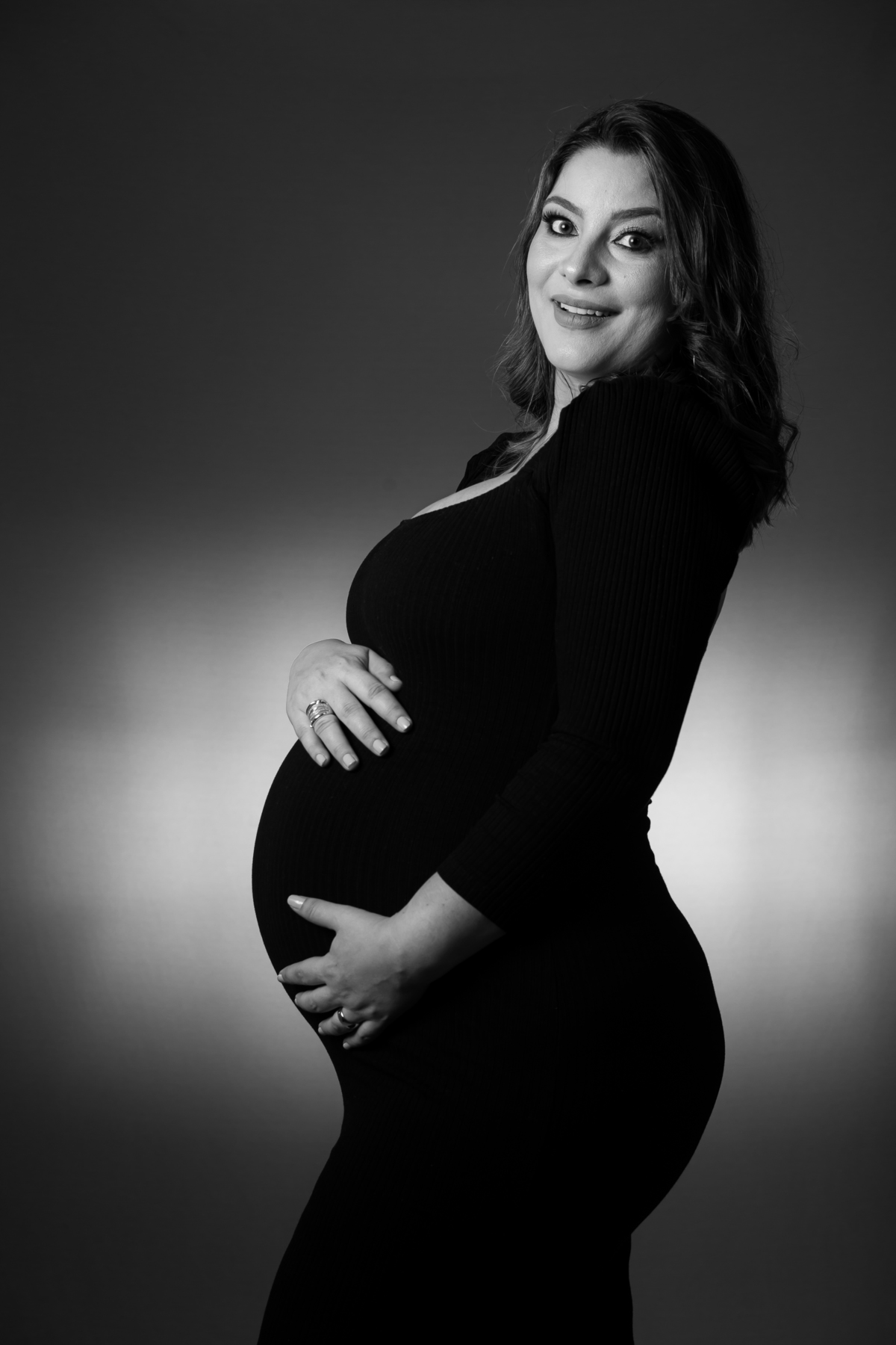 Ensaio de gestante em estúdio com detalhes de sombras e luz suave. Fotografia de grávida com rosto iluminado e natural.