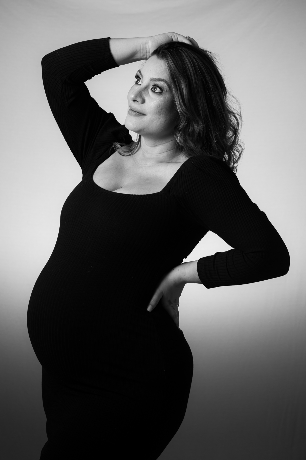 Sessão de fotos de grávida em estúdio com luz intensa. Ensaio de gestante com cenário simples e foco no rosto.