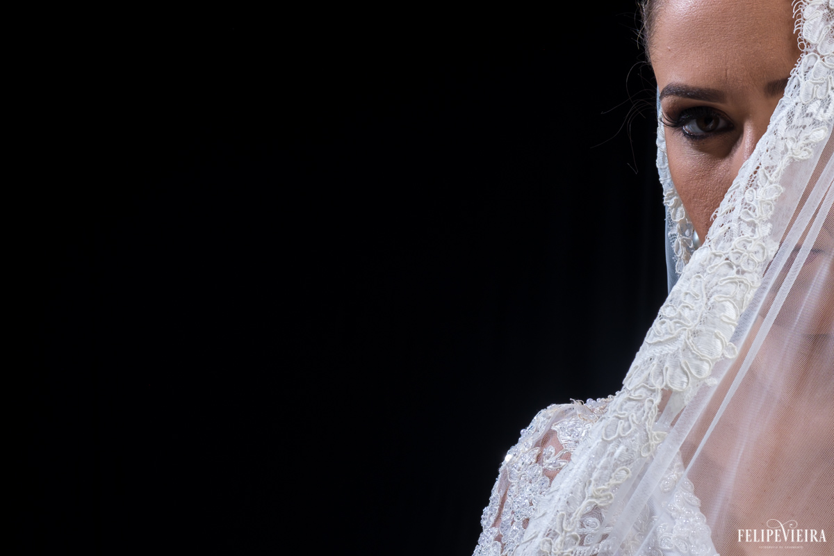 noiva olhando para frente com o véu na frente do rosto com um ar de mistério no estúdio felipe vieira fotógrafo de casamentos em guarapari