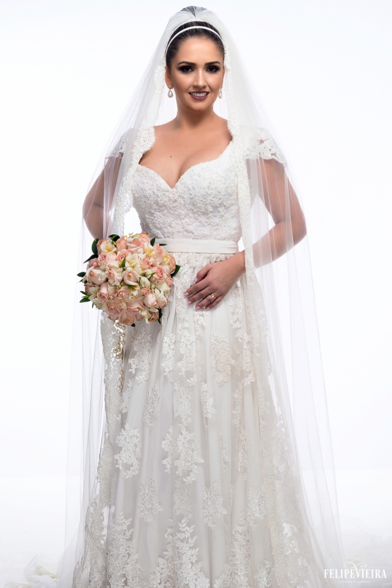 Noiva na frente do fundo branco segurando o buquê com o véu caindo pelos braços foto feita no estúdio felipe vieira fotógrafo de casamentos em guarapari