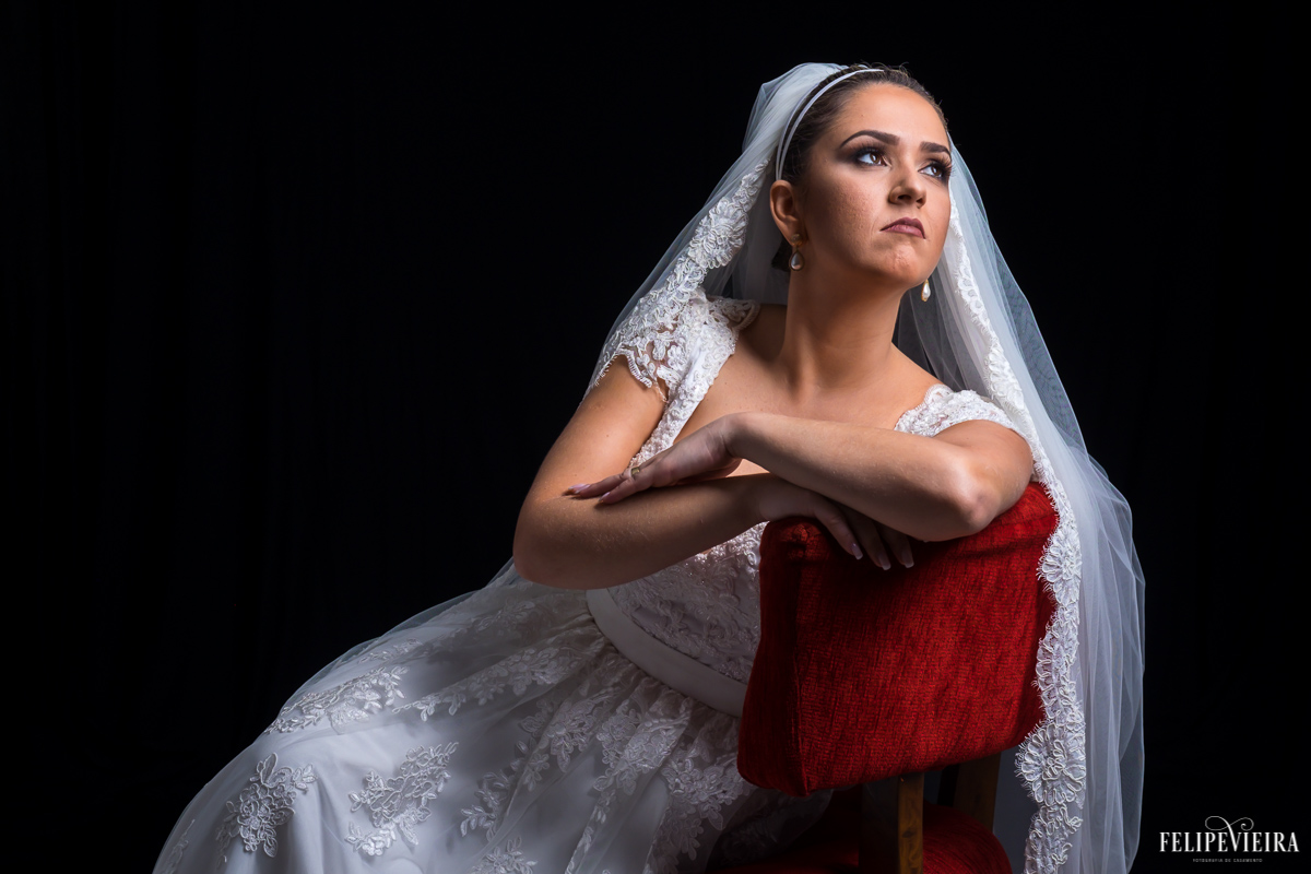 noiva sentada em cadeira vermelha olhando para luz em foto feita no estúdio felipe vieira fotógrafo de casamentos em guarapari