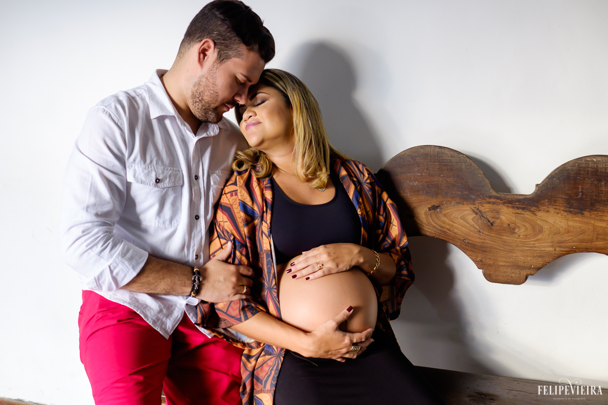 casal abraçado com as cabeças encostadas sentados em um banco no convento da penha foto feita por felipe vieira fotógrafo de gestantes