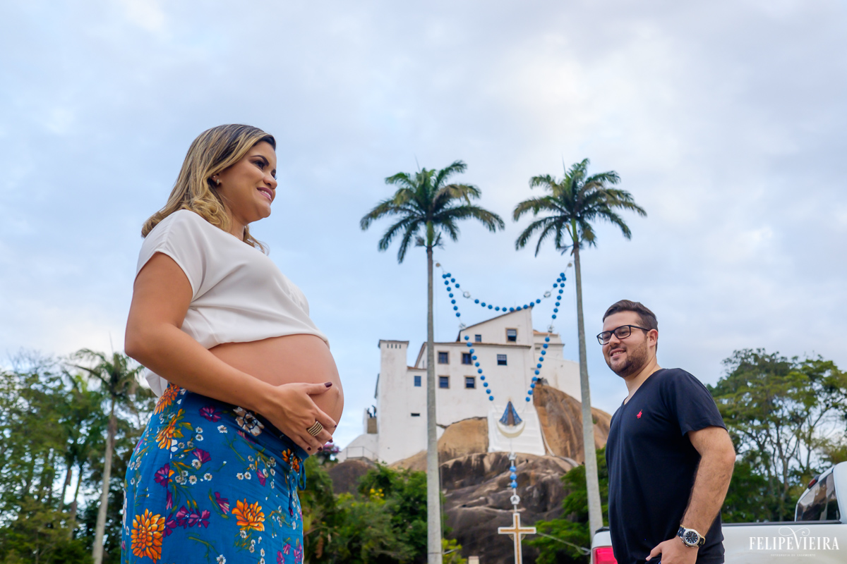 gestante e seu marido posando em frente ao grande terço do convento da penha em vitória foto feita por felipe vieira fotógrafo de gestantes