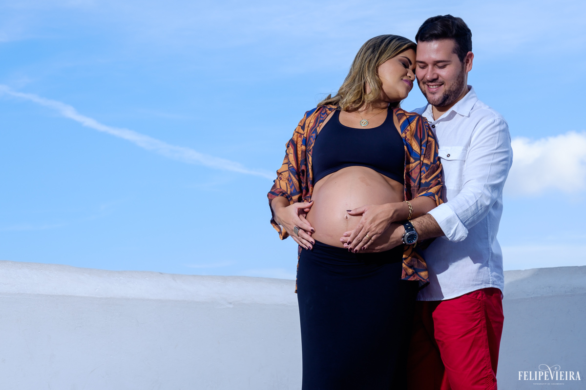 marido abraçado em sua esposa com a mão em sua barriga e sorrindo foto feita por felipe vieira fotógrafo de gestantes
