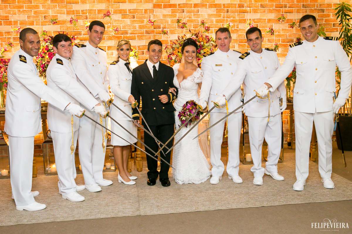 padrinhos militares posando com as espadas em frente a mesa do bolo com os noivos em foto feita por felipe vieira fotografo de casamentos em guarapari