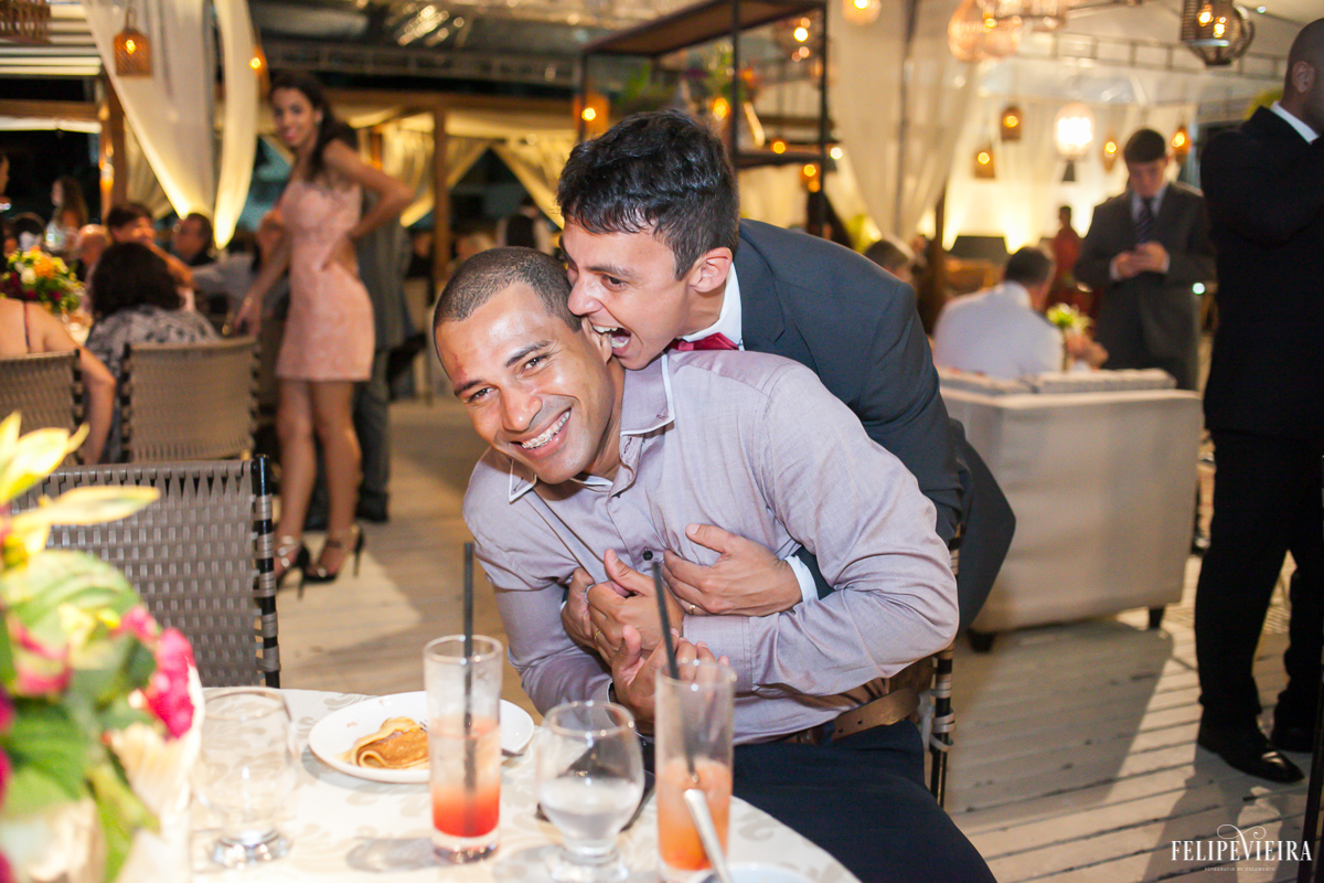 noivo mordendo a orelha do convidado em brincadeira na festa em foto feita por felipe vieira fotografo de casamentos em guarapari