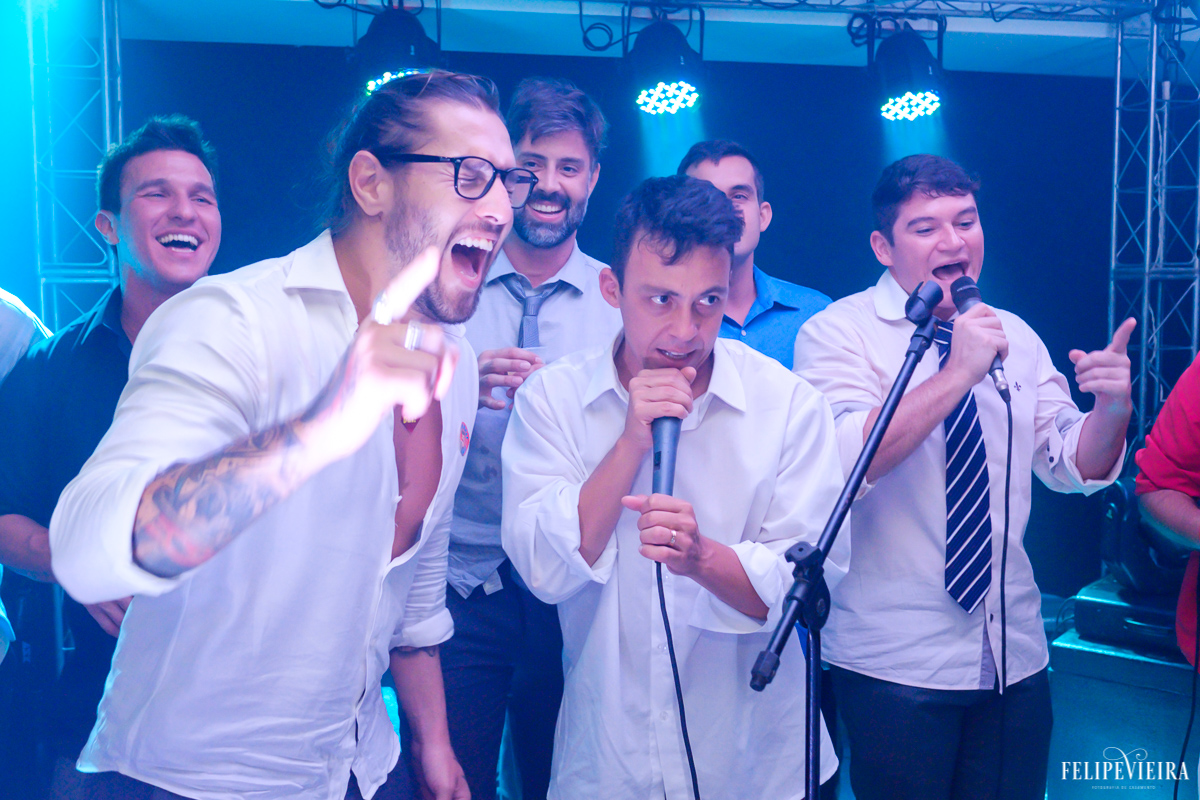 Noivo e amigos com os microfones da banda agitando a festa em foto feita por felipe vieira fotografo de casamentos em guarapari