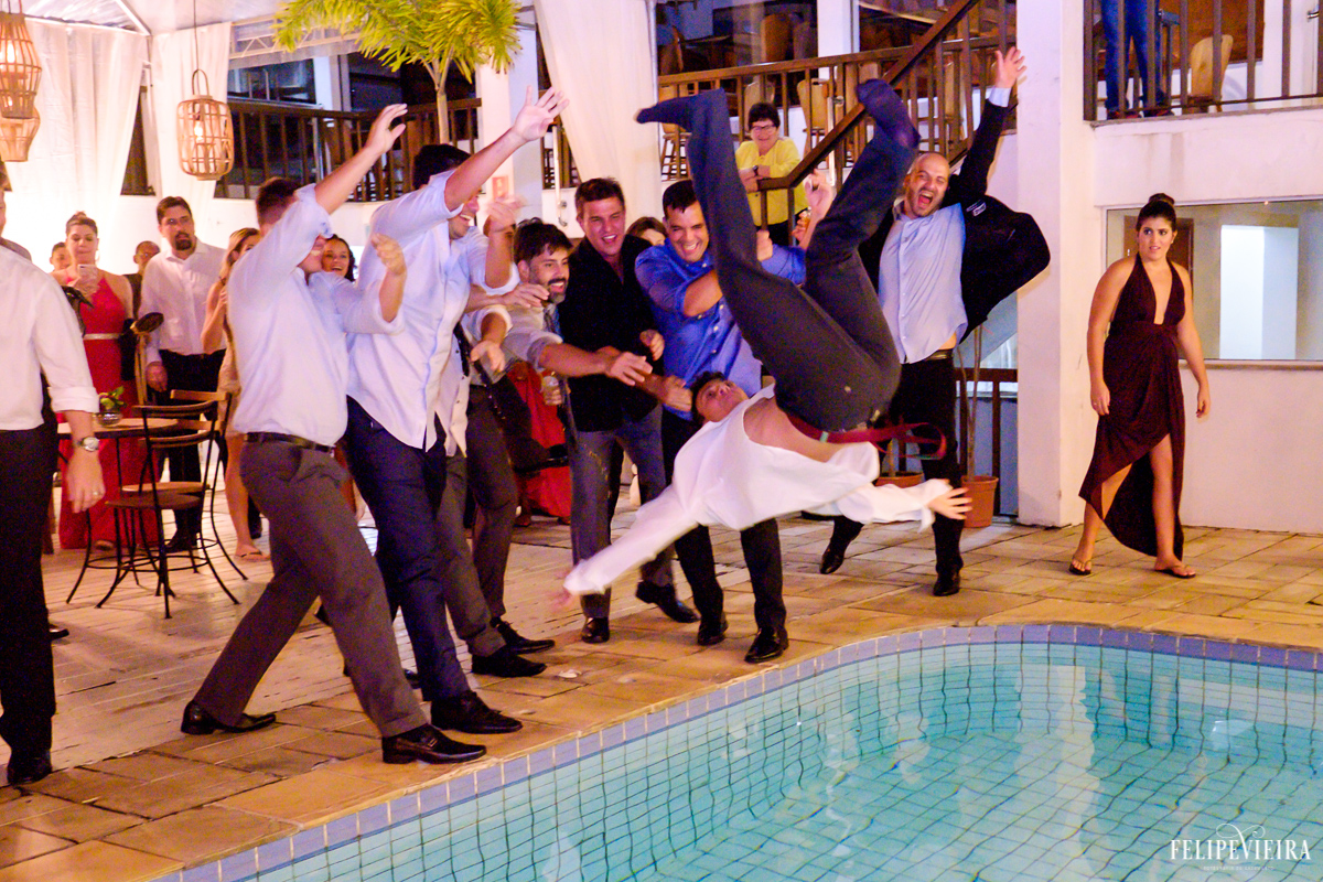 amigos do noivo o jogando na piscina com muita felicidade nos rostos em foto feita por felipe vieira fotografo de casamentos em guarapari