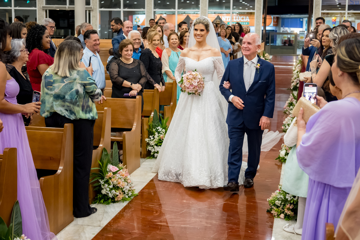 Vestido da noiva deslizando pelo corredor enquanto ela caminha até o altar.
