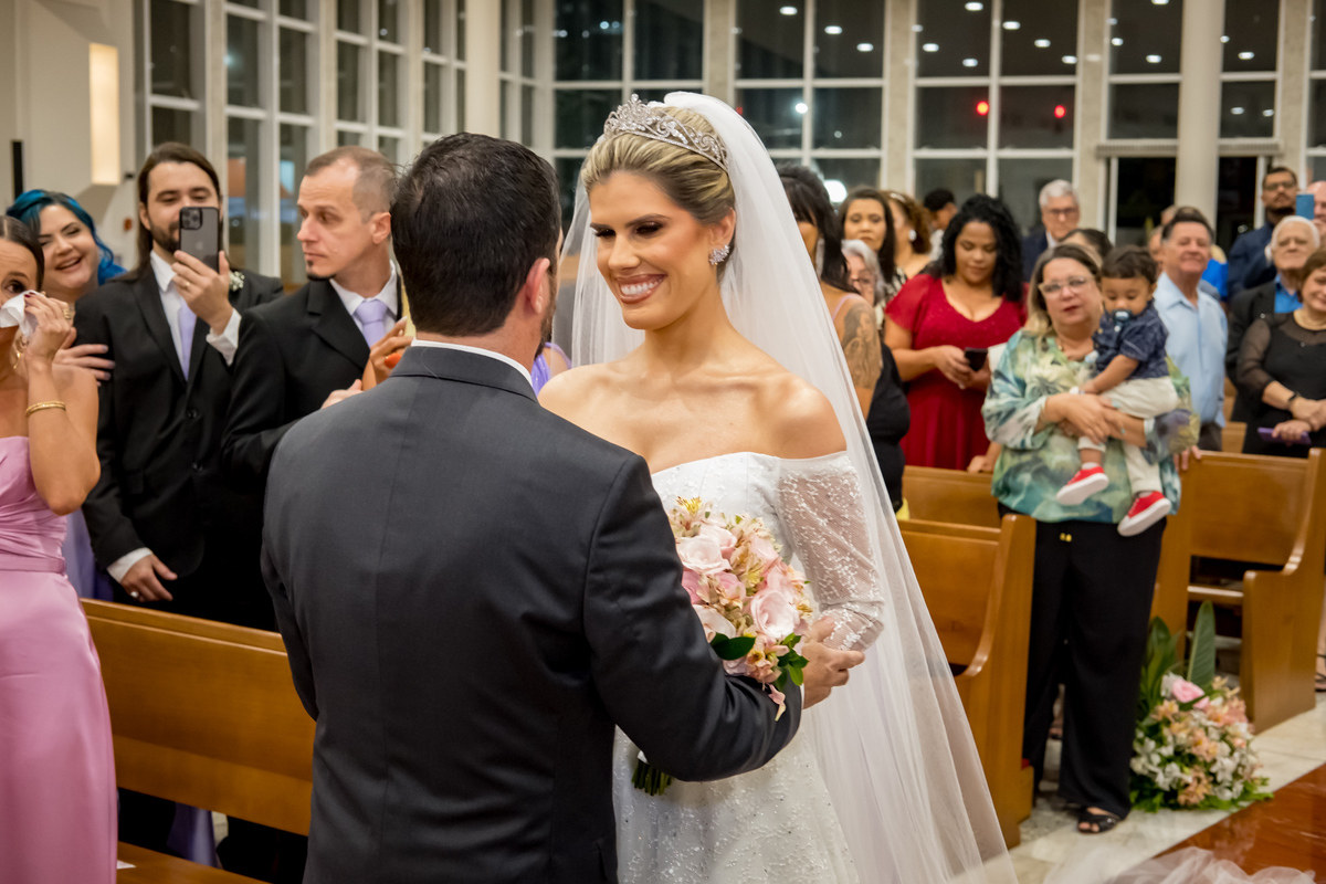 Noivos no altar sorrindo um para o outro, prontos para começar uma nova jornada.