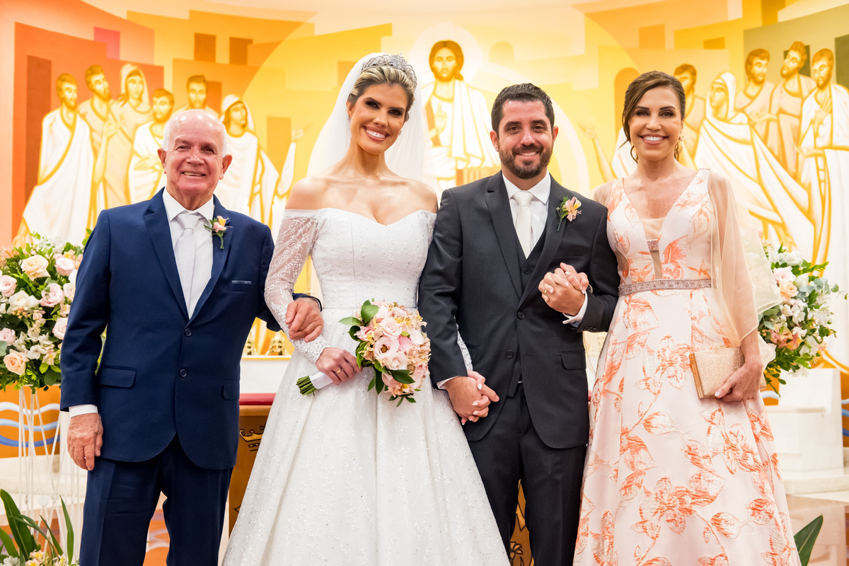 Noivos com os pais em foto após cerimônia no altar da igreja