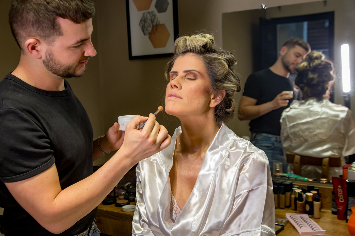 Maquiadora aplicando toques finais na maquiagem da noiva radiante.