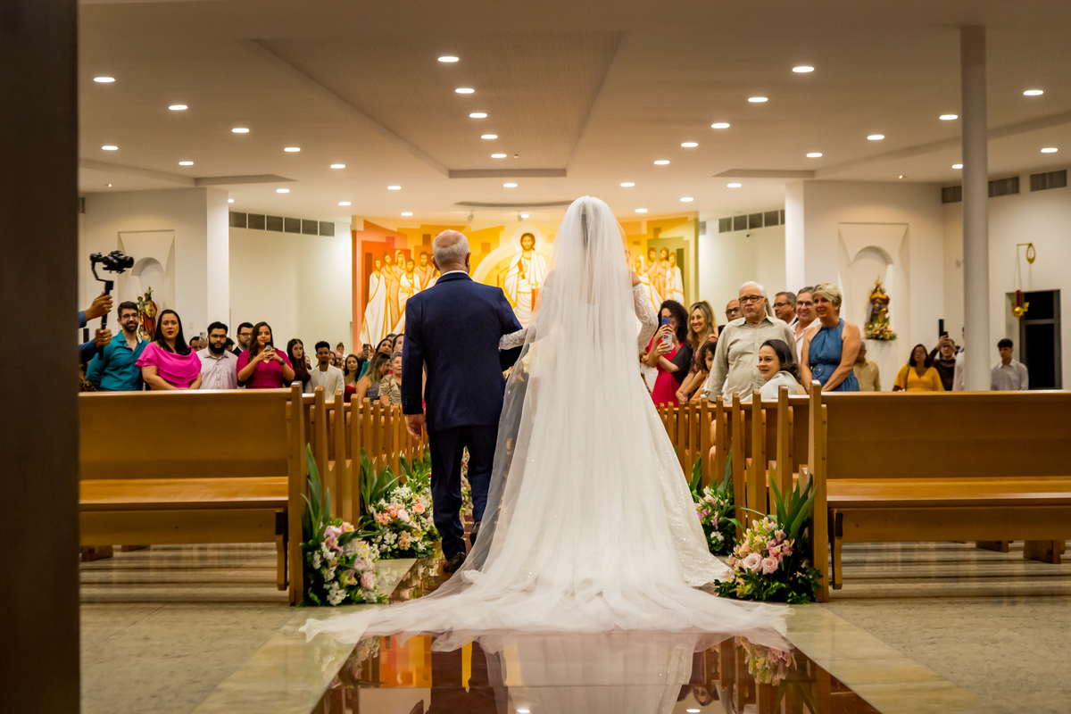 Vestido da noiva com cauda longa criando um efeito majestoso na entrada.