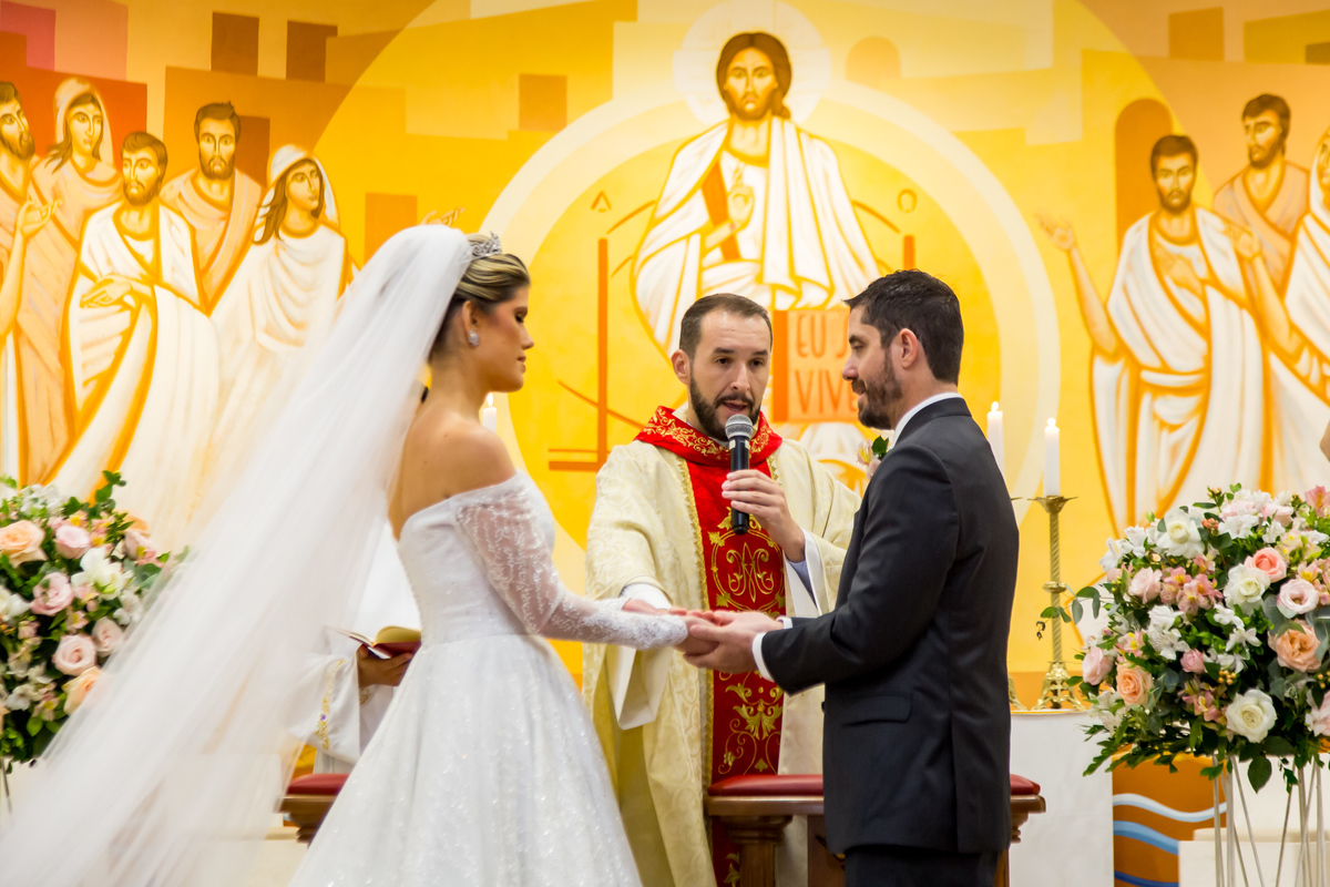 Noivos no altar segurando as mãos, simbolizando união e amor eterno.