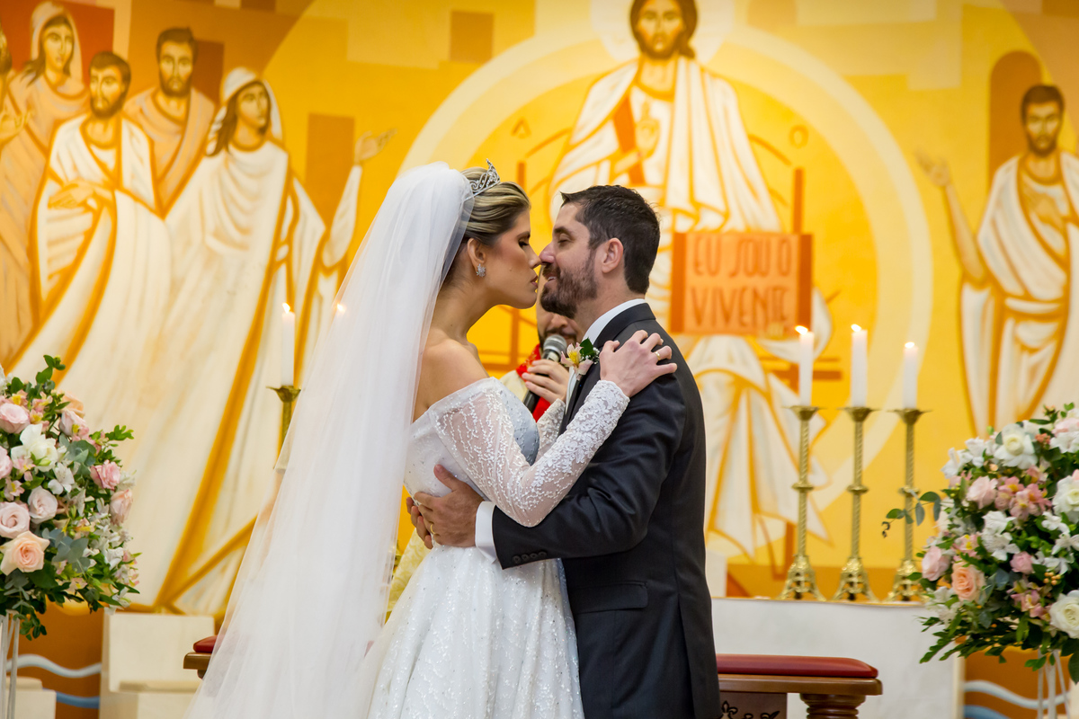 Noivos no altar compartilhando um beijo apaixonado após serem declarados casados.
