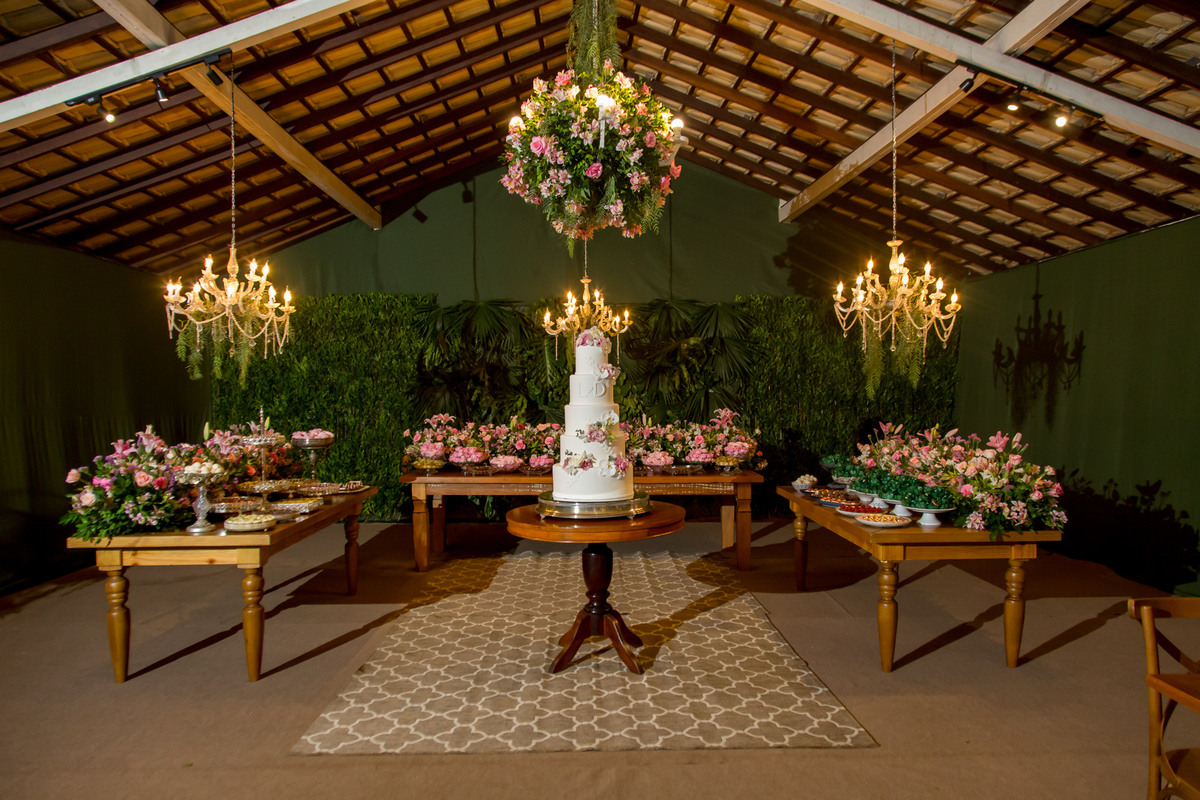 Mesa de bolo decorada com flores frescas e velas, criando um ambiente romântico.