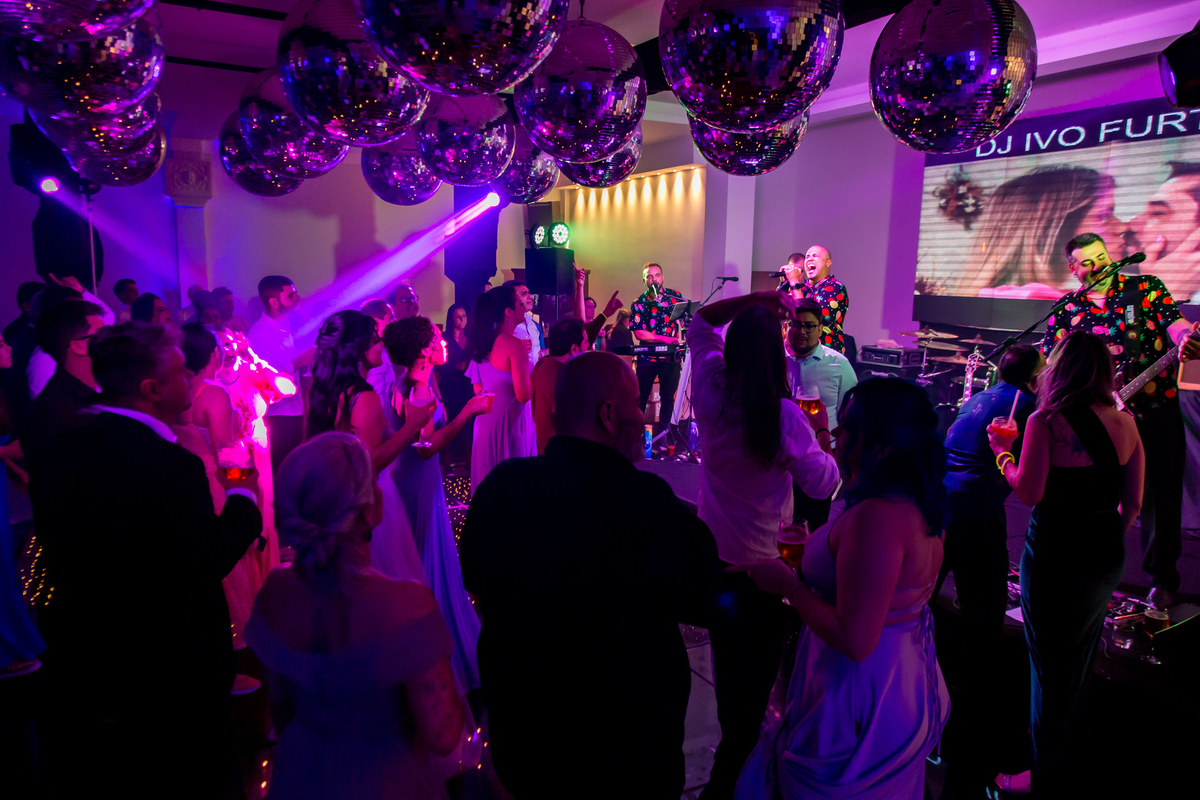 Convidados aproveitando cada segundo na pista de dança iluminada da festa.