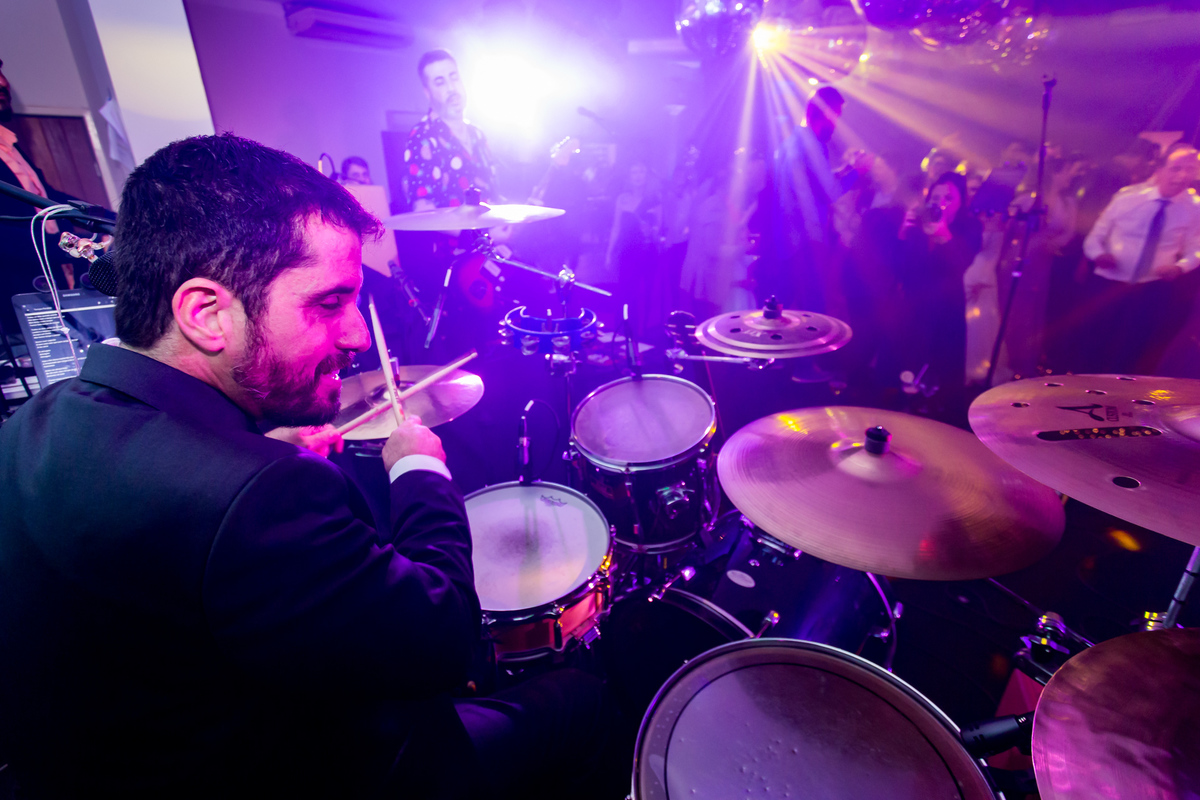 A festa de casamento ganha vida com uma banda que cativa todos os presentes.Noivo tocando bateria