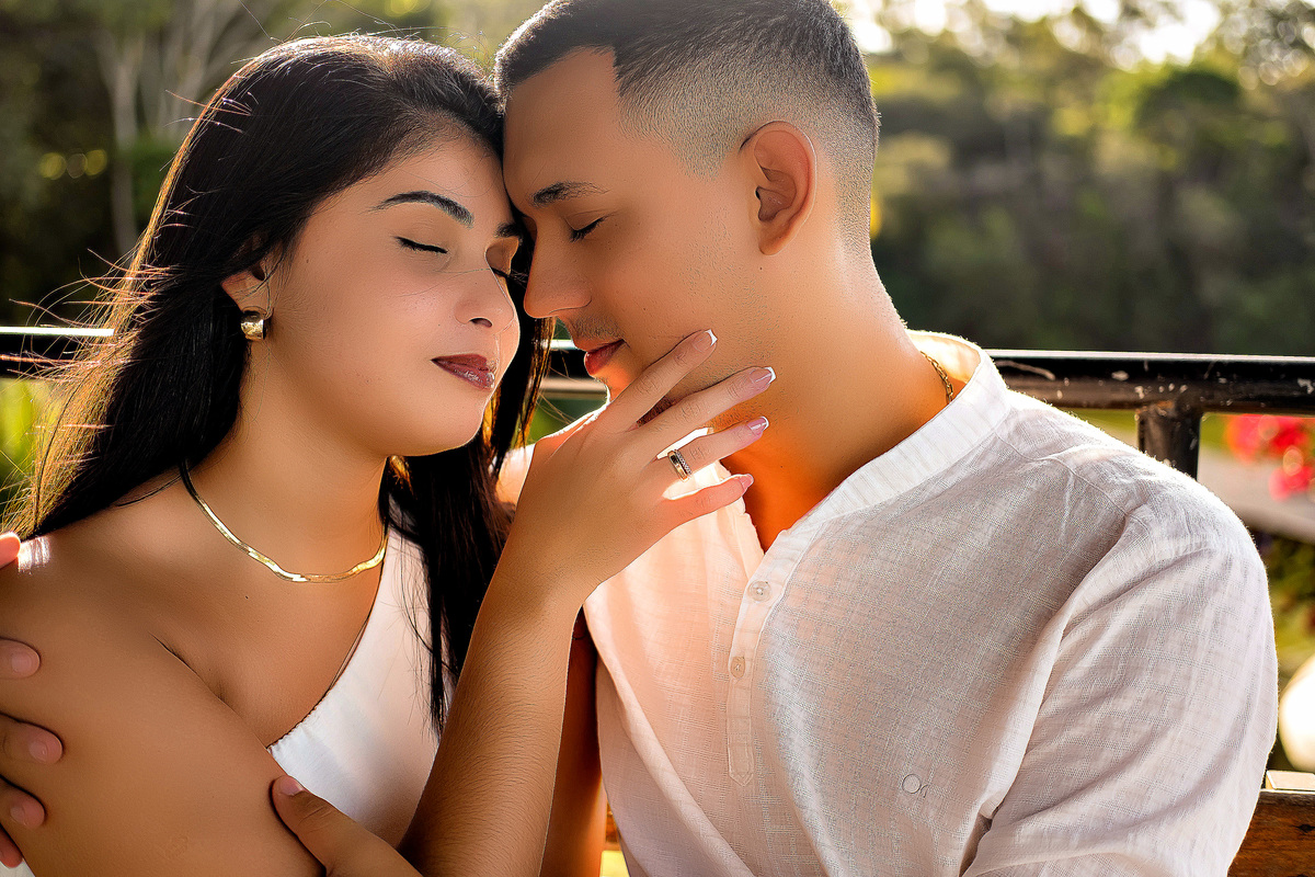 Casal se abraçando durante ensaio pré-casamento em Guarapari ele veste bata branca ela vestido branco ambos de olhos fechados em momento íntimo foto ao ar livre por fotógrafo especializado em casamentos