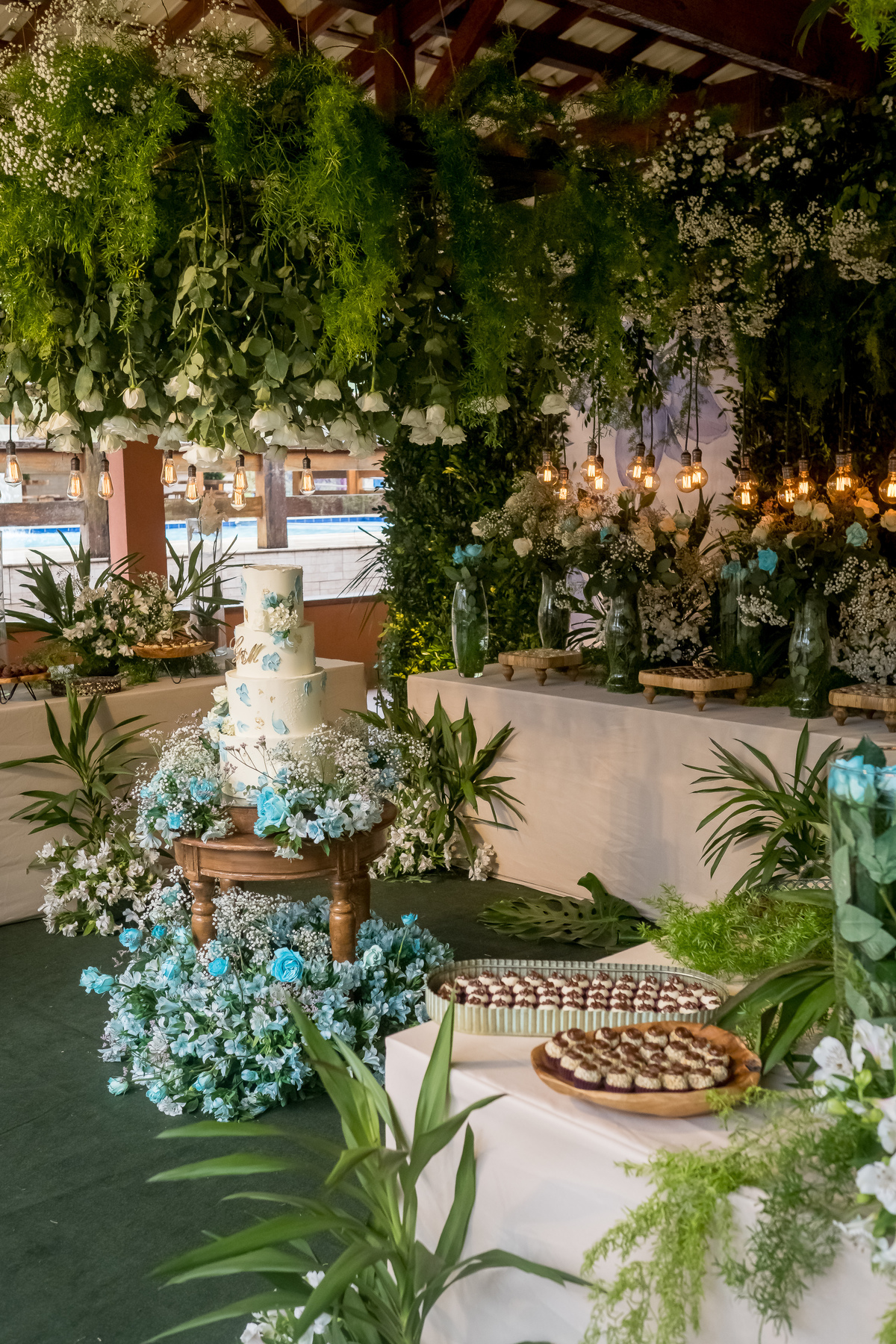 A decoração de casamento transforma o ambiente, com uma mesa de bolo deslumbrante e doces finamente preparados para encantar os convidados.