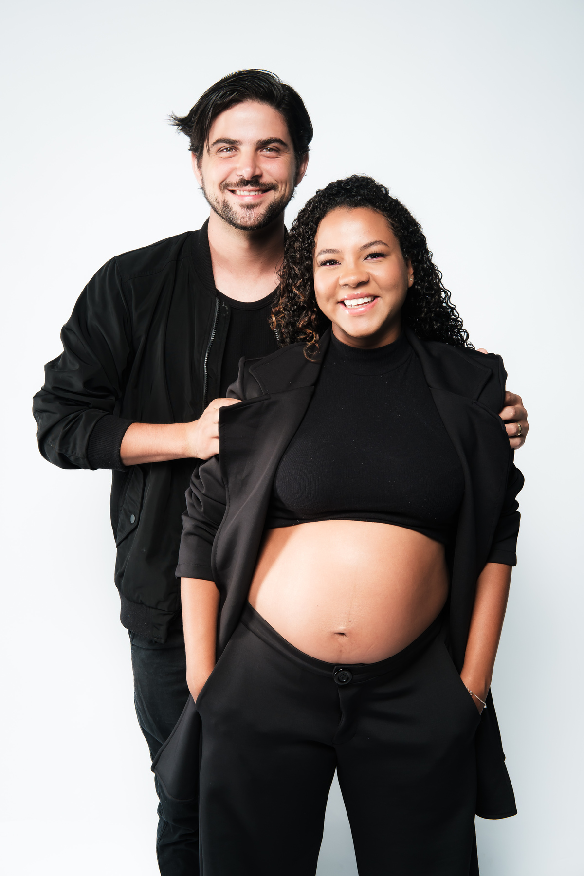 Book de gestante em estúdio com cenário clean e luz suave. Sessão de fotos de grávida com foco na postura e no sorriso.