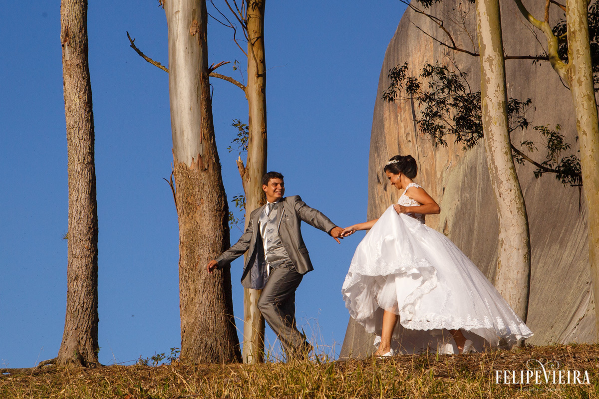 Noivos correndo em meio às árvores com a pedra azul de fundo foto felipe vieira fotografo de casamentos guarapari