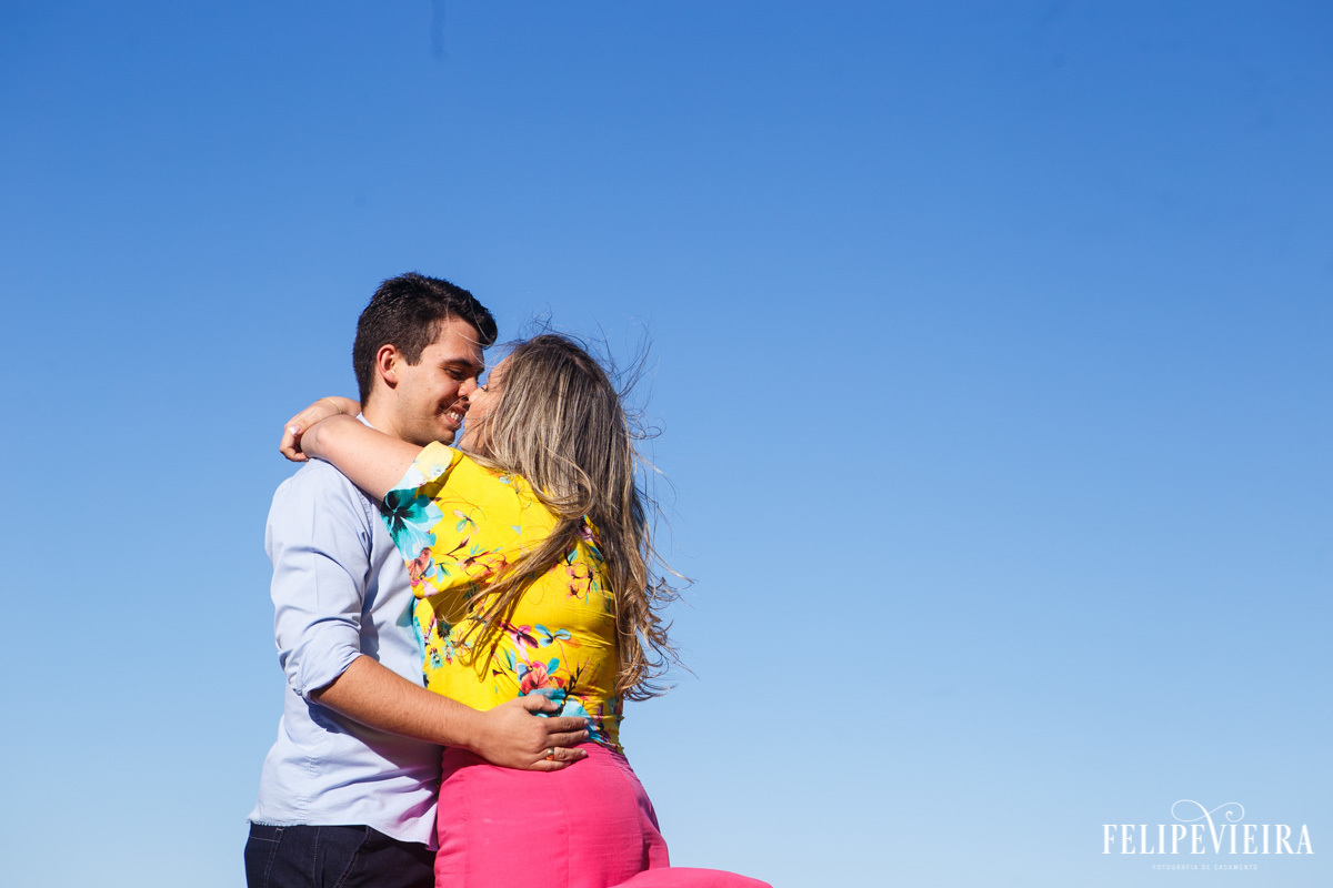 Ensaio de casal na praia com os noivos se abraçando com céu azul e pelo fotógrafo Felipe Vieira Fotografia de casamento em Guarapari fotografo de casamento Espírito Santo