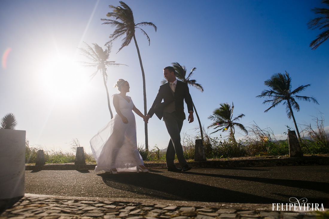 noivos andando de mãos dadas com coqueiros ao fundo ao vento foto feita por felipe vieira fotografo de casamentos em guarapari