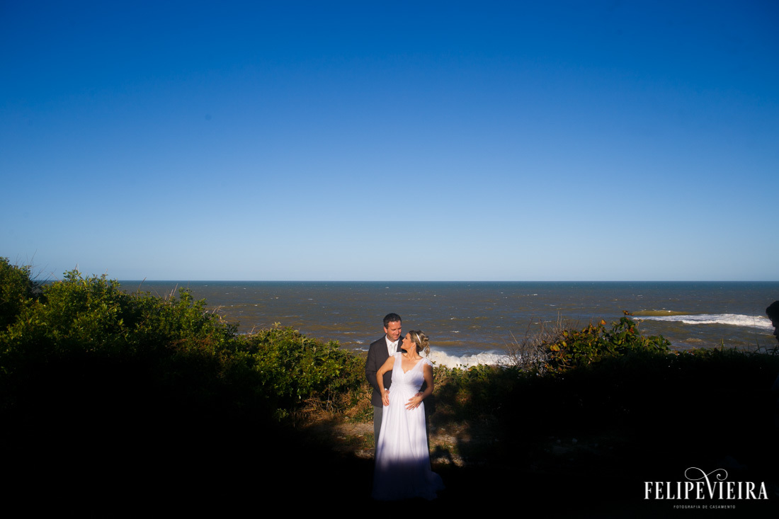 luz e sombras noivos abraçados com foco de luz e céu azul no fundofoto feita por felipe vieira fotografo de casamentos em guarapari