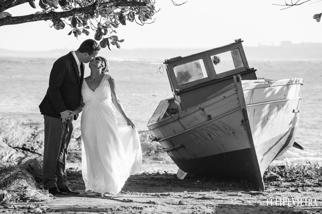 noivos se beijando ao lado de barquinho na praia foto em preto e branco foto feita por felipe vieira fotografo de casamentos em guarapari