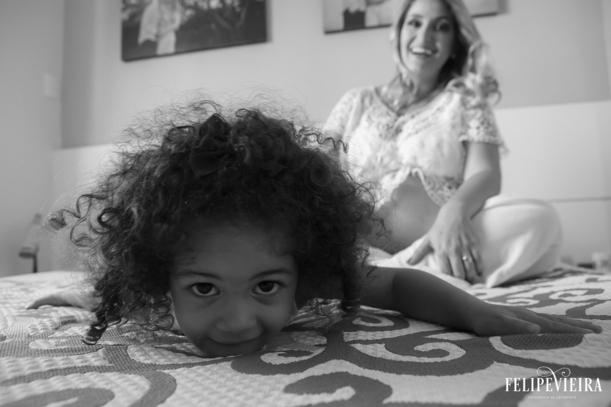 filha em primeiro plano com mãe sorrindo ao fundo em foto feita por felipe vieira fotógrafo em guarapari espírito santo
