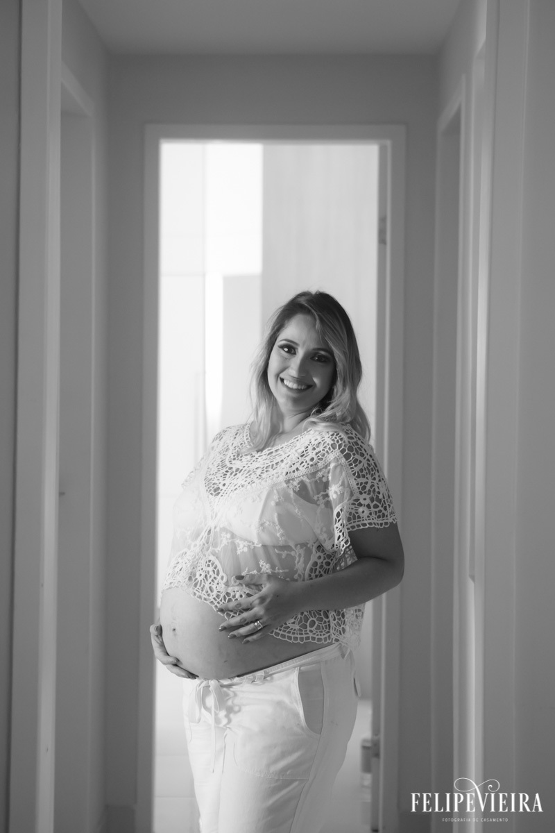 Gestante com mão na barriga e sorrindo em foto em preto e branco em foto feita por felipe vieira fotógrafo em guarapari espírito santo