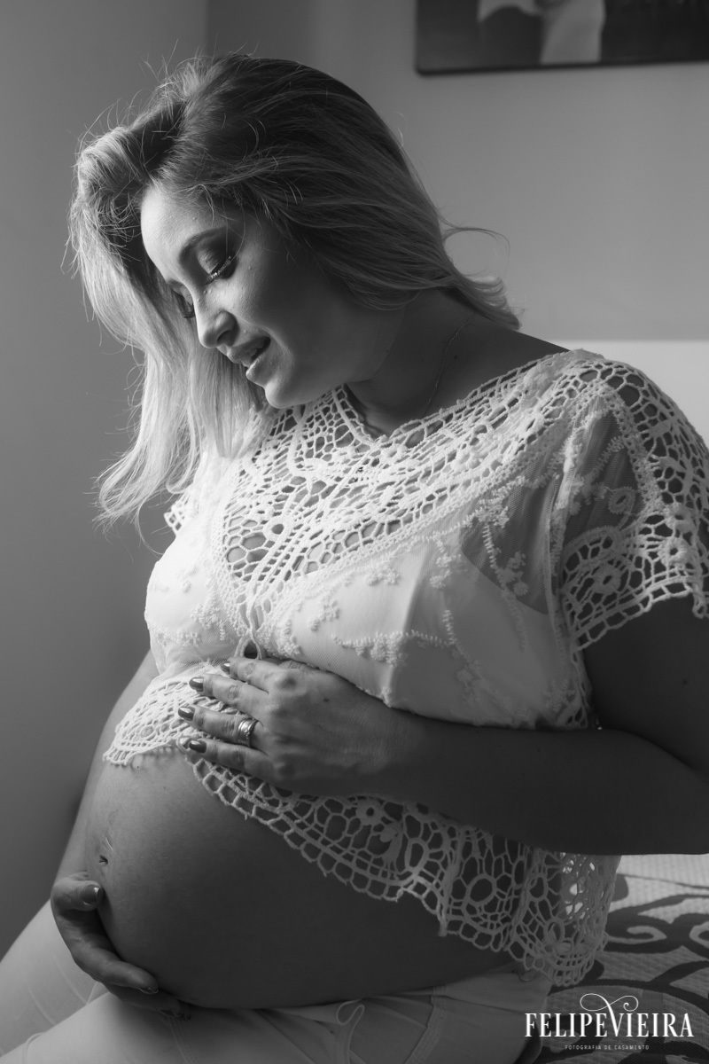 mãe com a mão na barriga sorrindo em foto em preto e branco em foto feita por felipe vieira fotógrafo em guarapari espírito santo