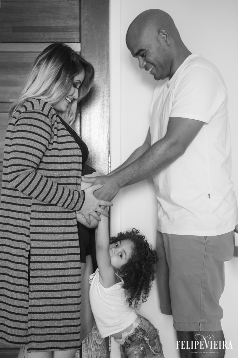 família reunida de mãos dadas e postas ao novo integrante em foto feita por felipe vieira fotógrafo em guarapari espírito santo