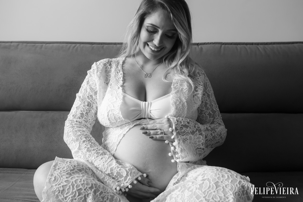 gestante sentada de pernas cruzadas em foto em preto e branco em foto feita por felipe vieira fotógrafo em guarapari espírito santo