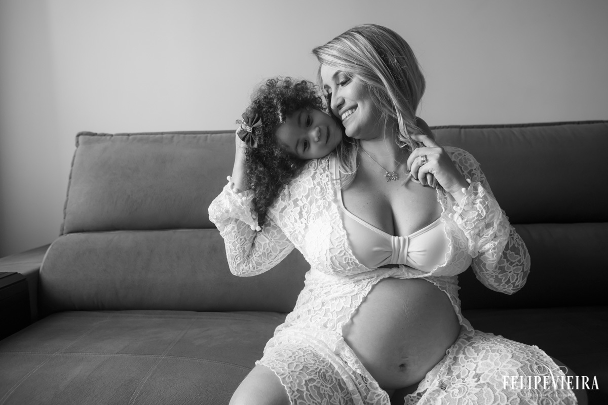 mãe sentada com filha a abraçando por trás em foto feita por felipe vieira fotógrafo em guarapari espírito santo