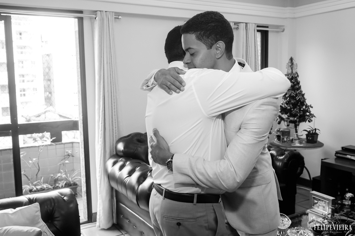 noivo abraçando padrinho enquanto se arrumam em foto em preto e branco em feita por Felipe Vieira fotografo de casamentos em guarapari e grande vitória
