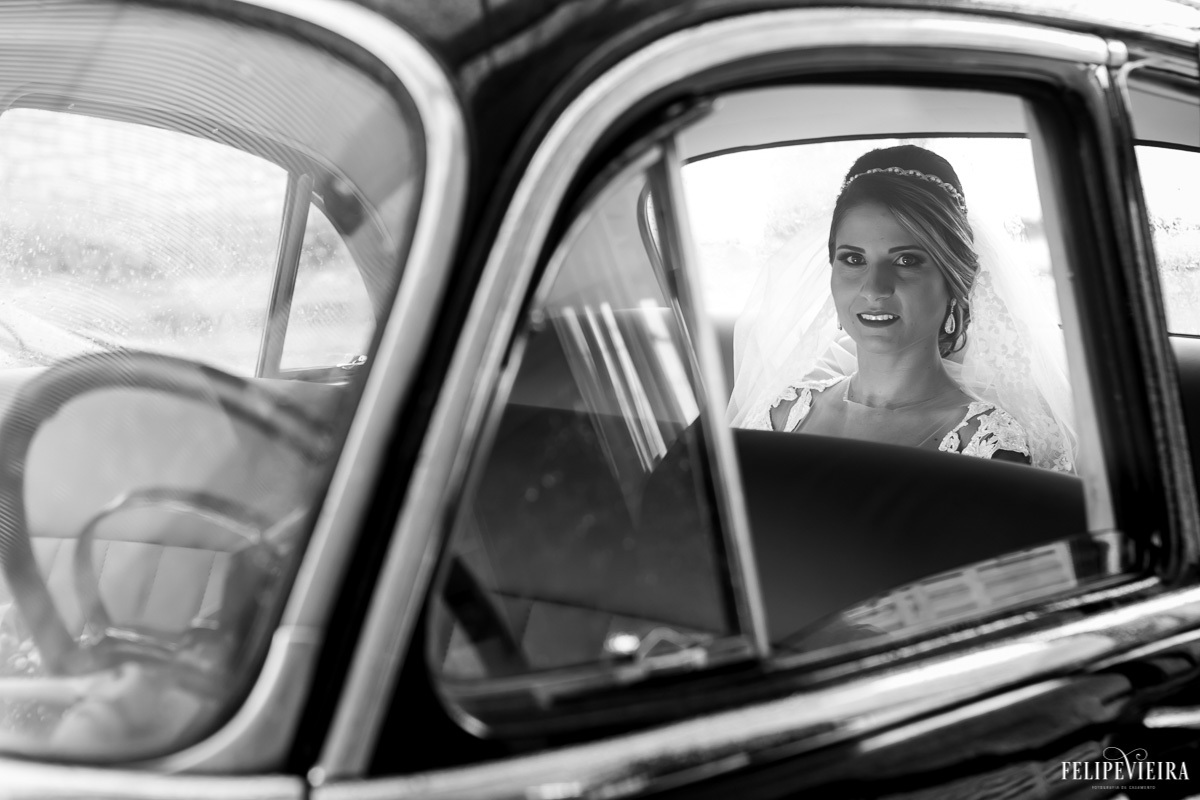 retrato da noiva sorrindo dentro do carro prestes a entrar na igreja em foto em preto e branco em feita por Felipe Vieira fotografo de casamentos em guarapari e grande vitória