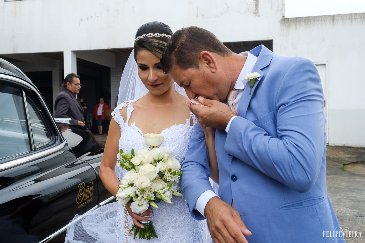 Noiva saindo do carro com seu pai beijando sua mão em feita por Felipe Vieira fotografo de casamentos em guarapari e grande vitória