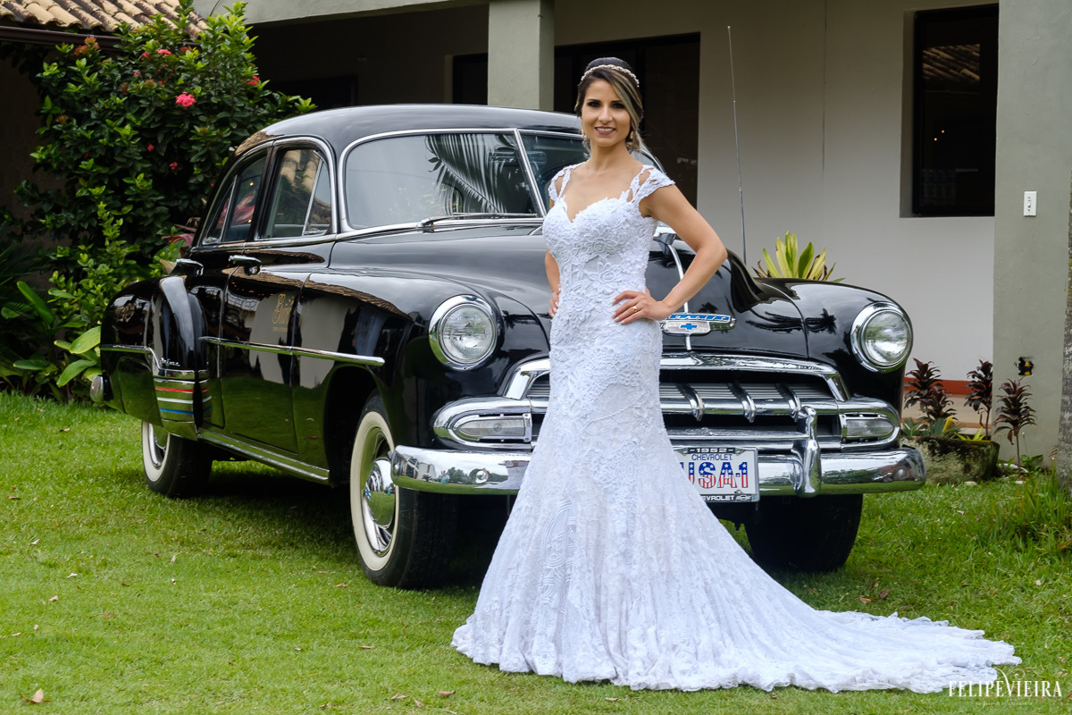 Noiva posando em frente ao carro com os detalhes do vestido em feita por Felipe Vieira fotografo de casamentos em guarapari e grande vitória