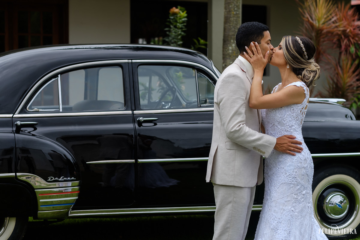 noivos se beijando em frente ao carro na festa em feita por Felipe Vieira fotografo de casamentos em guarapari e grande vitória