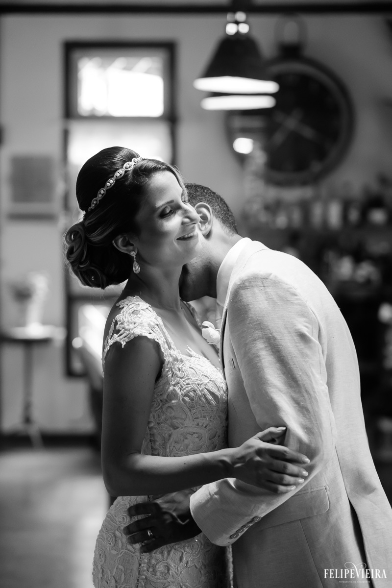 noivo beijando o pescoço da noiva enquanto ela sorri em foto em preto e branco em ensaio externo em feita por Felipe Vieira fotografo de casamentos em guarapari e grande vitória