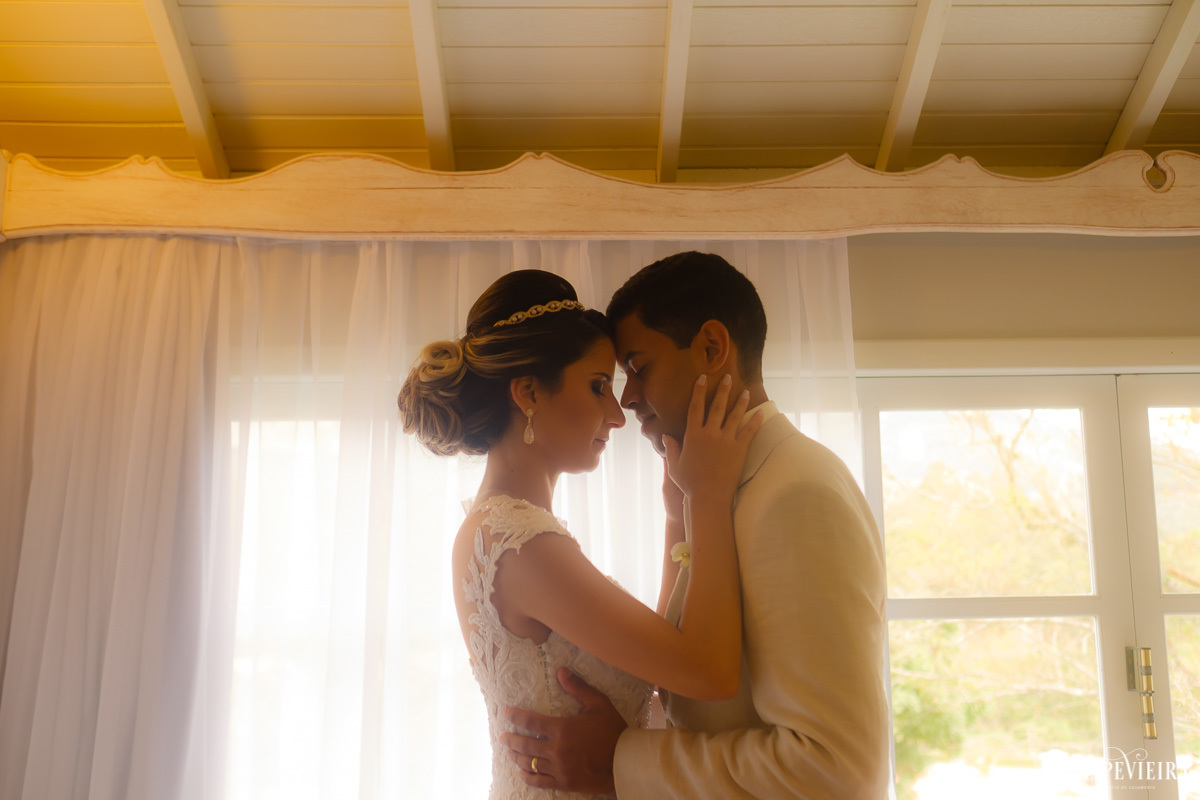 noivos de frente um para o outro com as testas encostadas em frente à janela e de olhos fechadosem ensaio externo em feita por Felipe Vieira fotografo de casamentos em guarapari e grande vitória