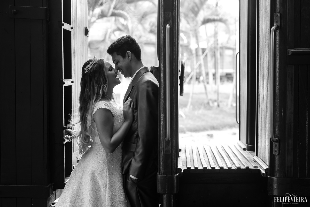 noivos de frente um para o outro em frente à janela e sorrindo em foto em preto e branco feita por Felipe Vieira fotografo de casamentos em guarapari e grande vitória