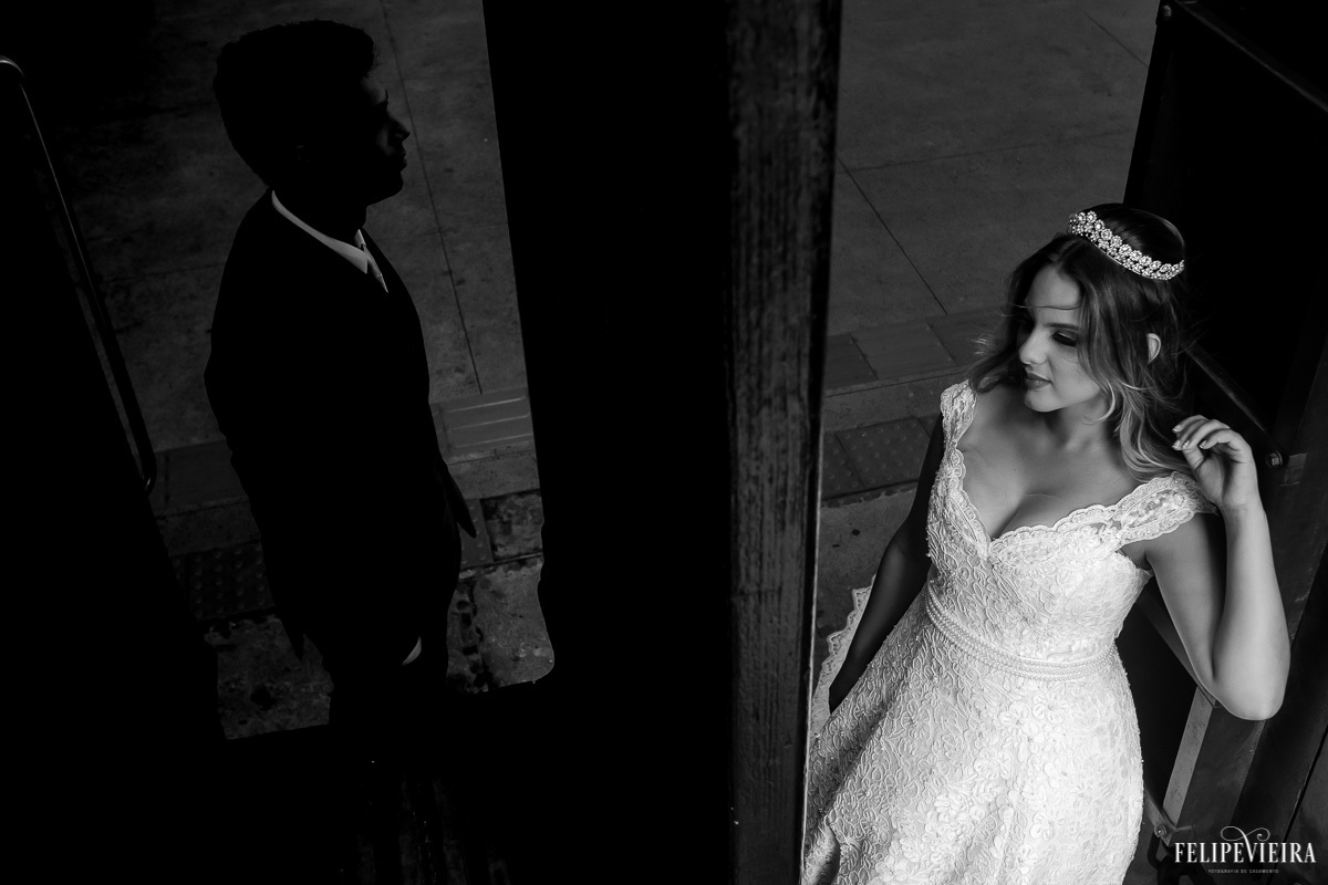 Jogo de luz com noiva no claro e noivo no escuro em janela em foto em preto e branco feita por Felipe Vieira fotografo de casamentos em guarapari e grande vitória