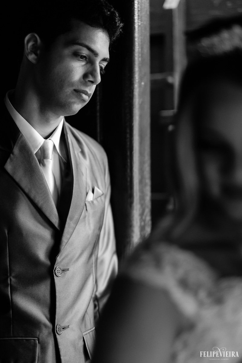 detalhes do terno do noivo com a noiva desfocada em primeiro plano em foto em preto e branco feita por Felipe Vieira fotografo de casamentos em guarapari e grande vitória