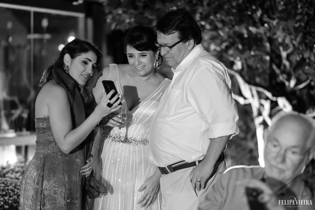 noivos olhando o celular de uma convidada em feita por Felipe Vieira fotografo de casamentos em guarapari e grande vitória